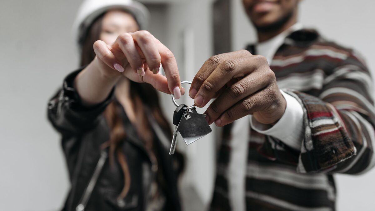 Junges Paar mit Schlüsseln in einer leeren Wohnung