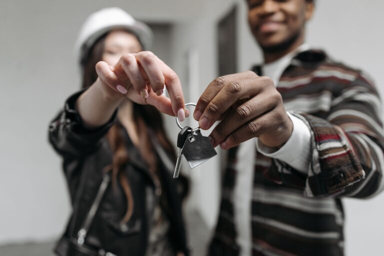 Junges Paar mit Schlüsseln in einer leeren Wohnung