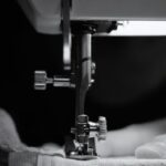 bernina - Detailed grayscale image of a sewing machine needle threading fabric, showcasing craftsman