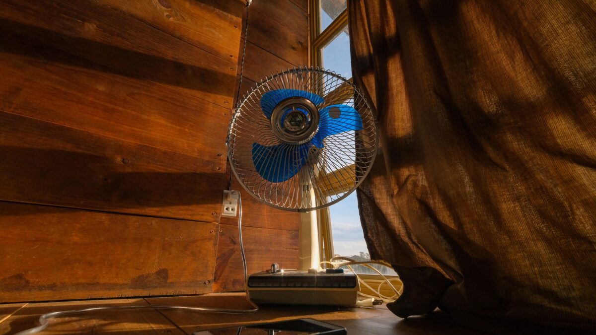Ventilator auf einer Kommode in einem hellen Schlafzimmer im Sommer