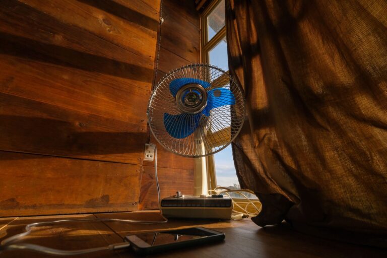 Ventilator auf einer Kommode in einem hellen Schlafzimmer im Sommer